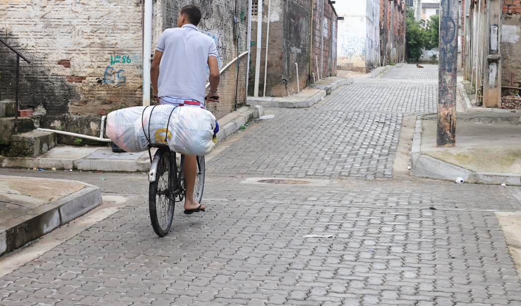 homem andando de bicicleta numa rua com piso intertravado